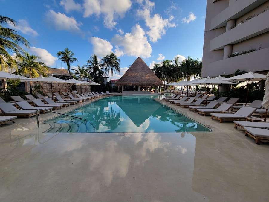 Piscina de hotel con camastros y palmeras frente al Caribe mexicano